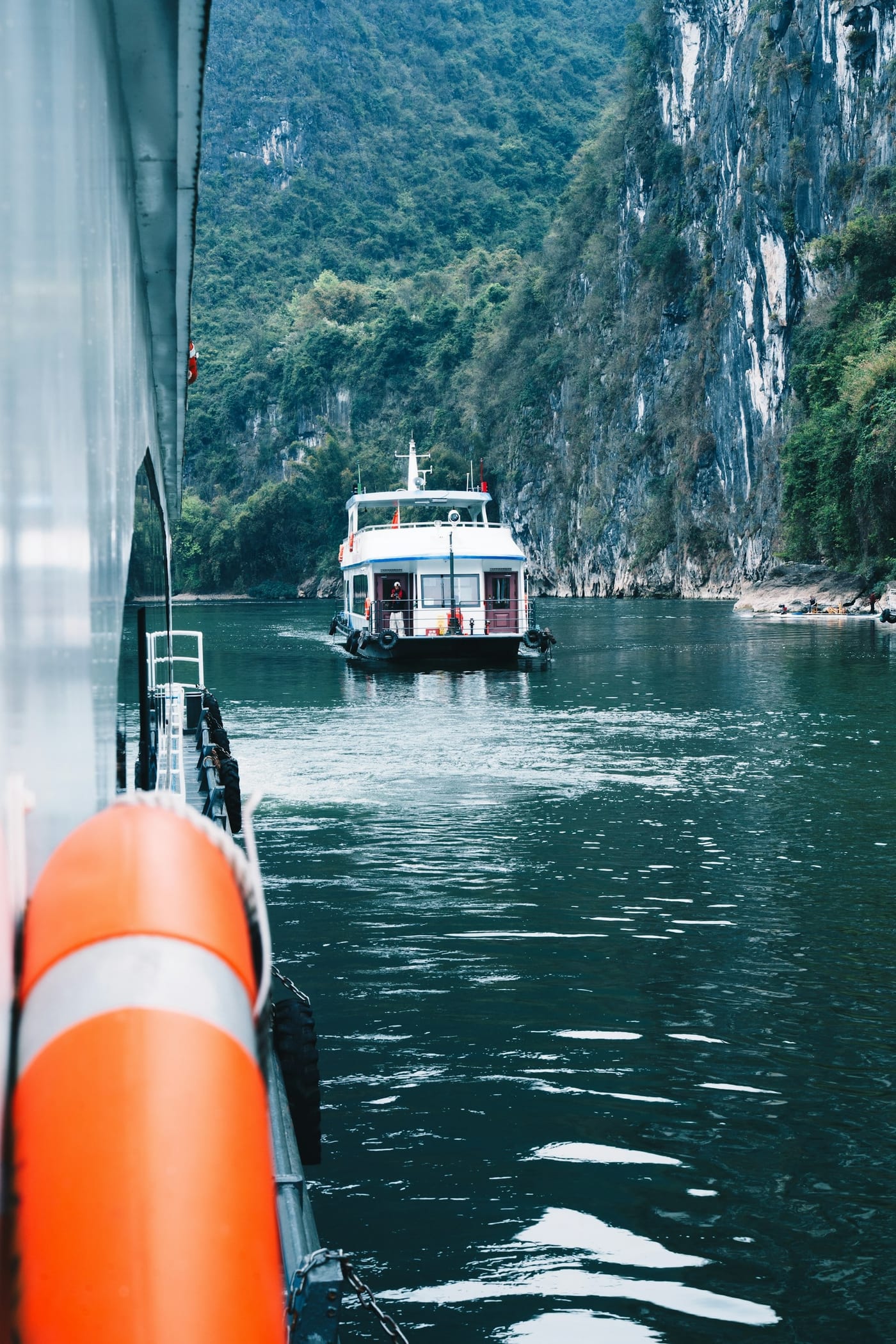 A tour boat on the Li River passing between steep karst cliffs